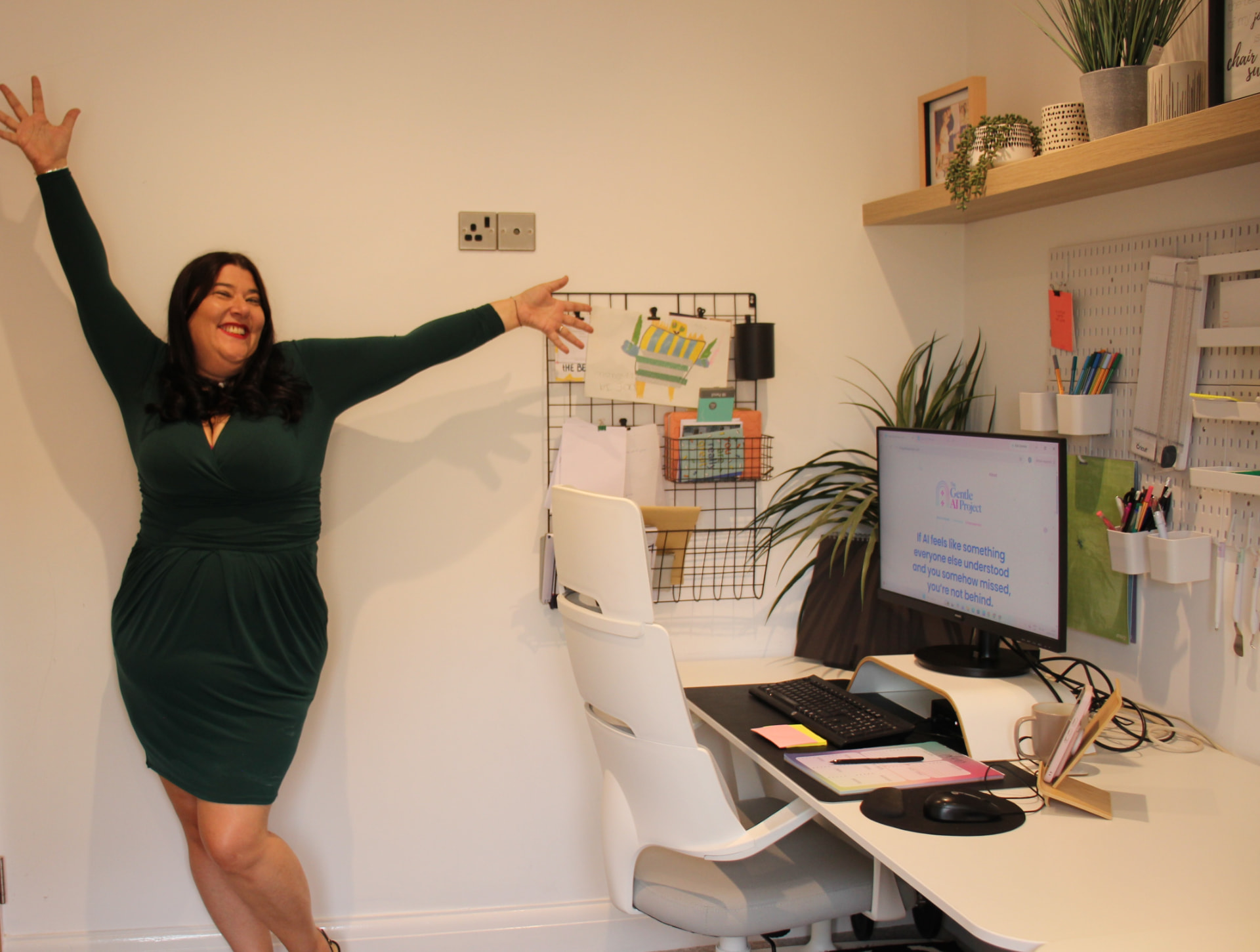 Victoria McLafferty smiling with her arms outstretched beside her desk